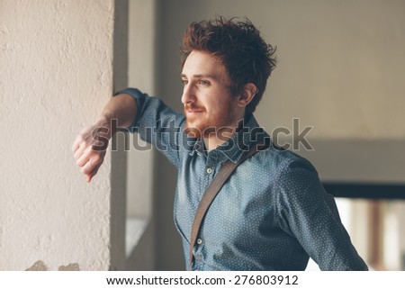 Young hipster looking away and leaning on a wall