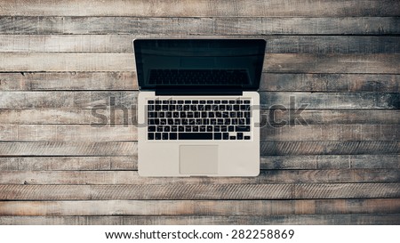 Grunge hipster wooden desktop with laptop, top view