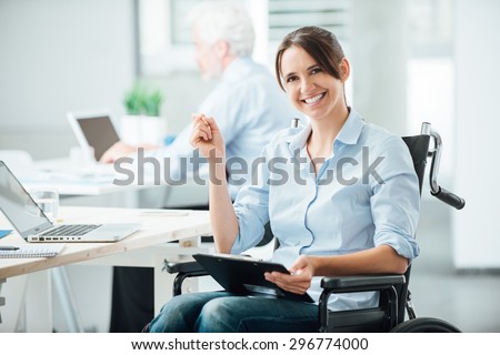 Happy female office worker in wheelchair holding a clipboard and smiling at camera, disabled people support at workplace