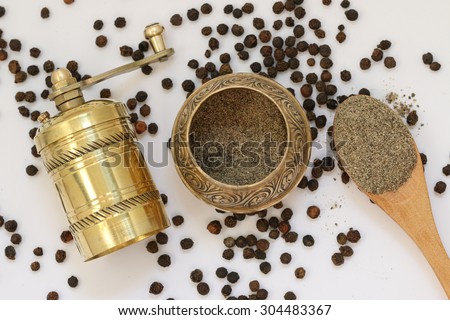 Brass pepper mill. Old oriental pepper mill and black pepper. Black pepper corns and black pepper powder.