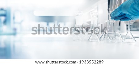 hand of scientist in blue glove with test tube and flask in medical chemistry lab banner background	