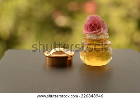 bottle of honey for health ans cosmetic with one of pink rose