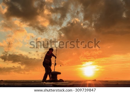 A man fishing silhouette at sunset and dark cloud.