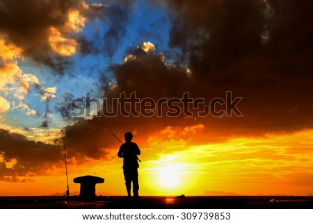 A man fishing silhouette at sunset and dark cloud.