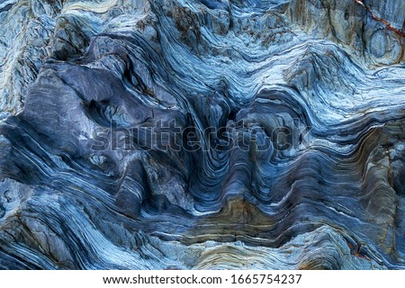 Detail of a rock with variants of blue. Rock full of curves and smooth cuts resulting from the erosive effect of sea. Close up rocks, texture dramatic and colorful erosional water formation. Stone