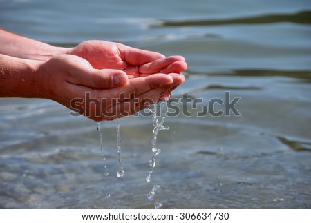Human hands splashing pure water from river