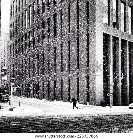 A person walking in front of a building on a snowy day.
