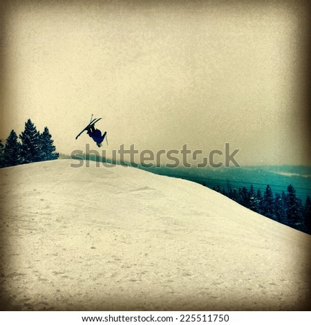 A lone skier flipping through the air on a snowy hill.