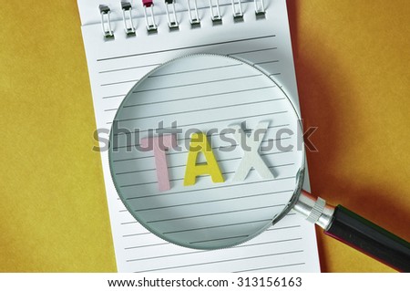 Magnifying glass ,words of GST and TAX on notebook .Goverment service tax & tax