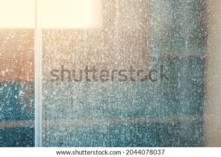 Removing hard water stains and deposits in bathroom. Stains drops on glass shower doors. Cleaning bathroom concept.