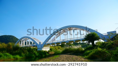 old arch bridge across the creek in LAMPHUN THAILAND. White color arch bridge with blue sky