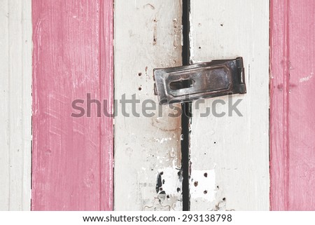 Old metal handle on pastel wooden door. Textured background. Vintage effect.