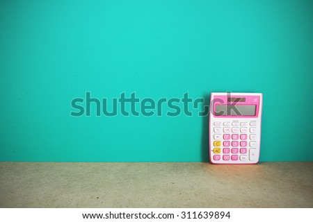 Pink calculator on table front mint green background. Vintage effect.