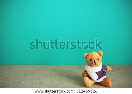 Teddy bear retro toy on table front mint green background. Vintage effect.