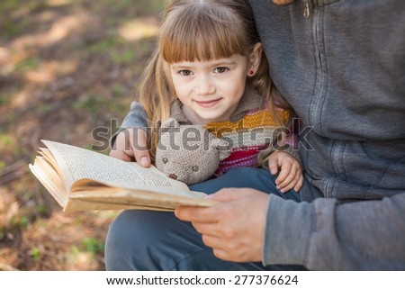 Daddy daughter reading a book outdoors
