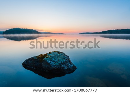 Stone lying in still lake at sunrise Stockfoto © 