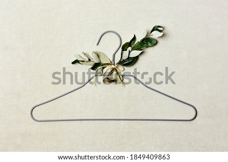Iron hanger with sprig of the tree with leaves on linen background. Natural aestetic, Eco-friendly, Chic, Cozy, Sustainable Sale concept. Zero waste Black friday. Space for text.