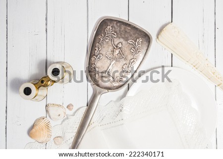 Vintage classic composition with antique binoculars, ivory fan, seashells and ceramic plate and cotton white napkin a white wooden background shabby chic style dance theme