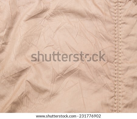 Beige coat cloth with seam stitches and crumpled texture