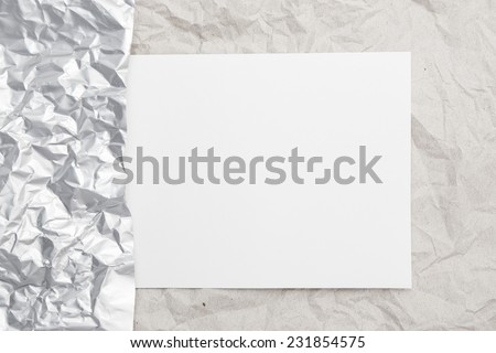 Sheet of paper on a crumpled beige paper texture with border of sheet of silver foil for text writing