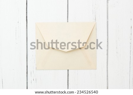 Old ivory paper envelope closed on a white wooden background.