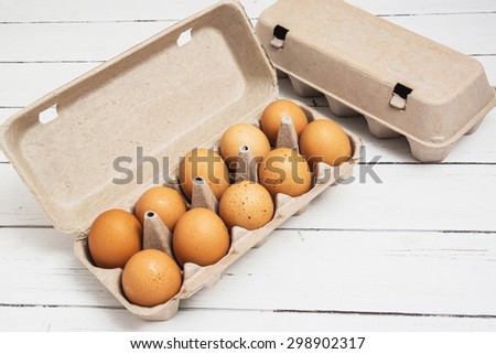Fresh ginger eggs packed in a gray ecological paper container on a white wooden table background