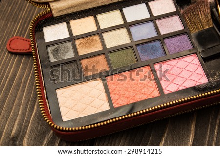 Used cosmetics pallete case isolated on a white wooden table