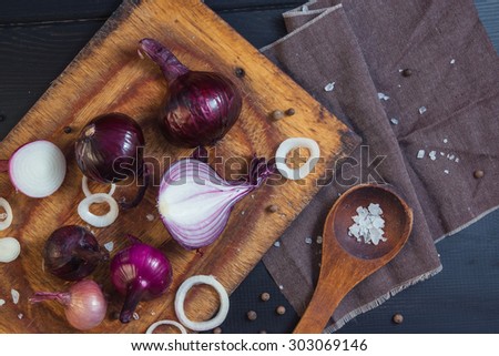 Cutted onion on a wooden board with salt and pepper in a wooden spoons. Still life for a food blog