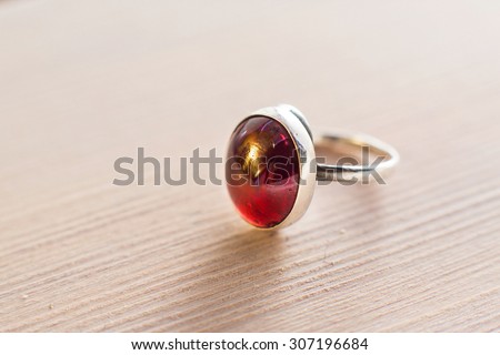 Silver ring with garnet stone cabochon on a white wooden background
