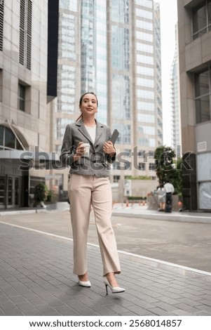 Similar – Foto Bild Elegante ethnische Geschäftsfrau zu Fuß in der Innenstadt mit Tasse Kaffee