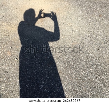 Shadow of a person taking a picture with a cell phone. Room for copy space.