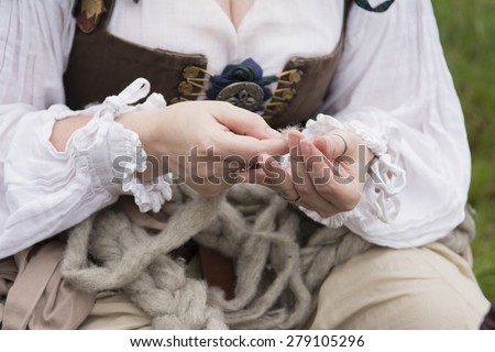 A woman spins wool by hand dressed in Renaissance costume.