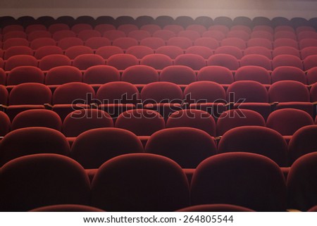 Red seats in theater hall with lens flare, wide shot
