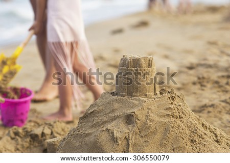 Sand tower and children building sand castle in the background