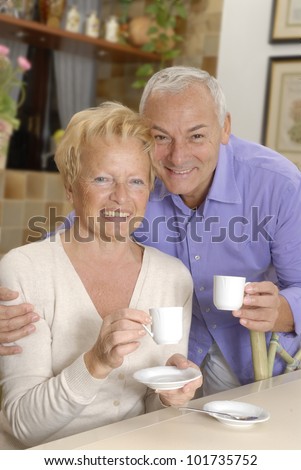 Happy senior couple drinking coffee in the kitchen.