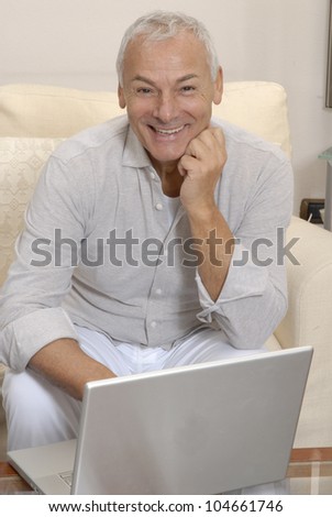 Smiling elderly senior man with laptop at home