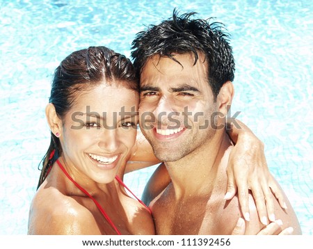 Hispanic young couple enjoying in a swimming pool.