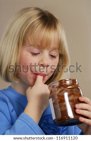 Little girl eating chocolate cream.Kid eating nut chocolate cream.