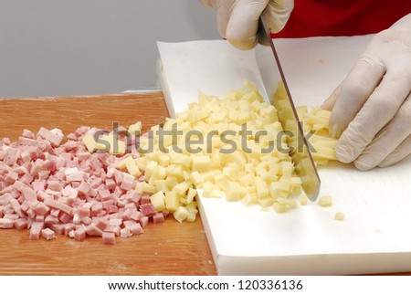 Hand cutting cheese and ham,preparing food.
