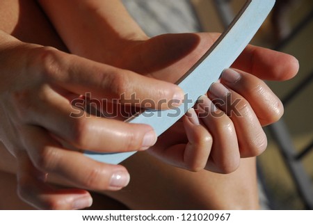 Body-care of hands. Woman polishing fingernails with the nail file.