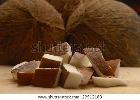 Wedges of coconut on wood table,couple coconuts and pieces.