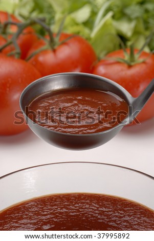 Metallic spoon with boiled fresh tomato cream on it. Pouring fresh tomato cream