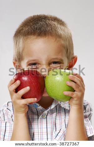 A little boy holding two apples.