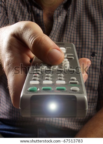 Remote controller in a hand.  Hand pointing a remote control,  Changing channels with a remote control.