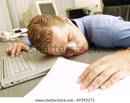 exhausted young businessman sleeping at his desk.