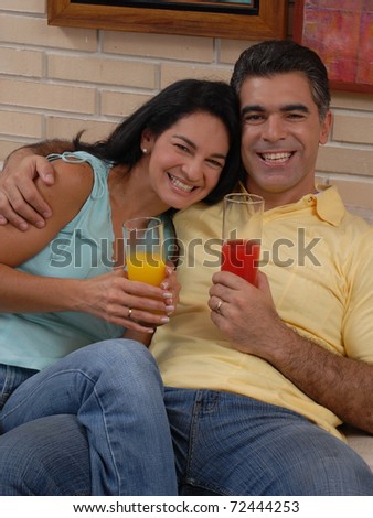 Mid adult couple drinking fruit juice in a living room. Couple drinking and sharing in a living room.