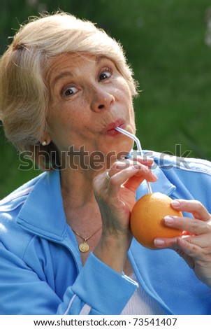 Mid adult woman drinking orange juice. Mid adult woman holding fresh oranges.