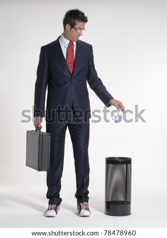 Young businessman dropping a paper in a waste basket. Young businessman dropping a paper in a trash bin.