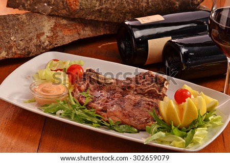 Grilled beef steak dish on red wine bottles and rustic background