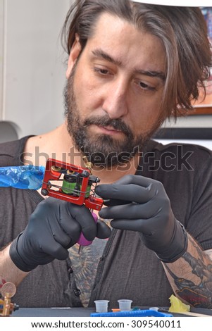 Tattoo artist preparing his ink machine gun before get start working.